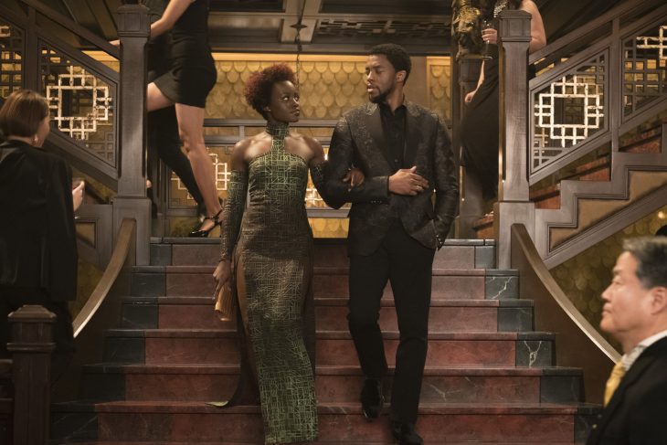 T'Challa y Nakia tomados de las manos, bajando las escaleras juntos, escena película Black Panther, Chadwick Boseman, Lupita Nyong'o