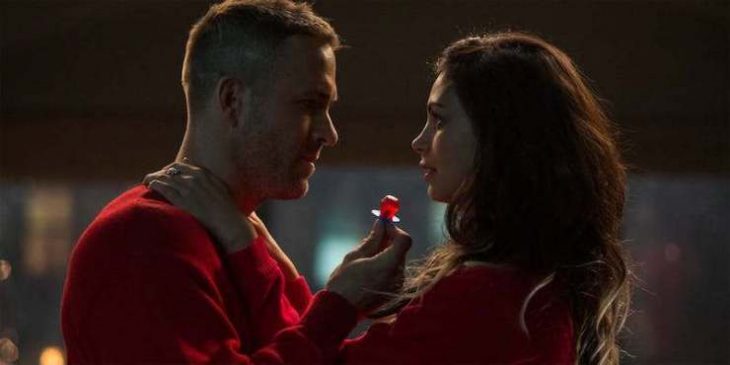 Wade Wilson y Vanessa Carlysle usando suéteres de color rojo, mirándose a los ojos, escena película Deadpool 1, Marvel, Ryan Reynolds