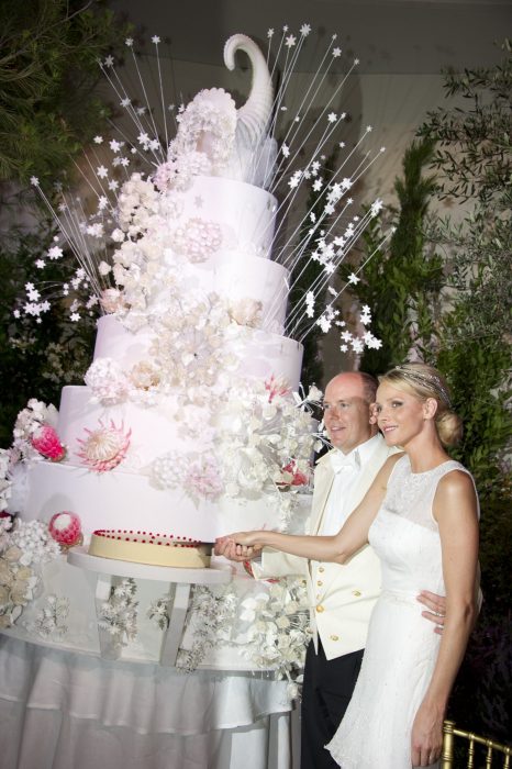 Pareja de novios abrazados mientras cortan una de las tortas de su pastel de bodas 