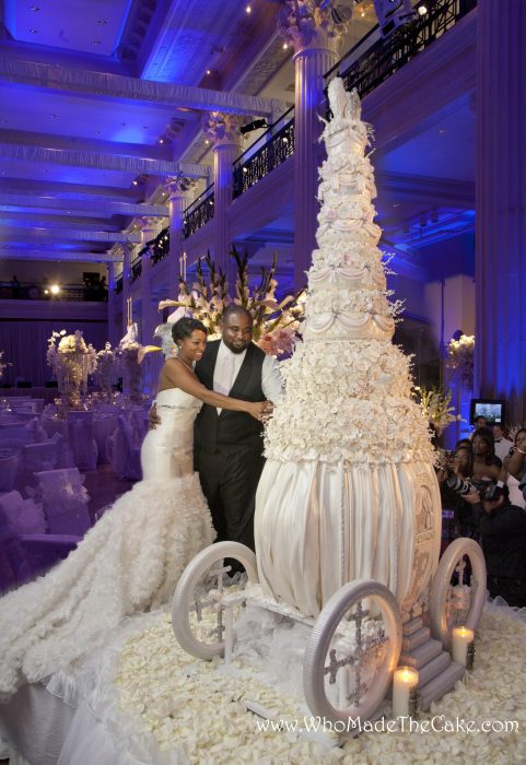 Pareja de novios parados frente a un pastel de bodas de varios pisos para cortar su primera rebanada en un pastel montado en una carroza