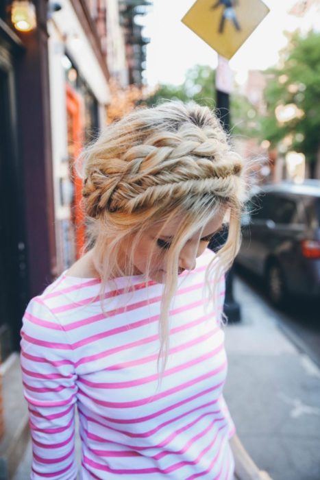 Ideas de peinados para el calor; chica rubia con blusa de rayas rosas y blancas, peinada con dos coronas de trenzas diferentes