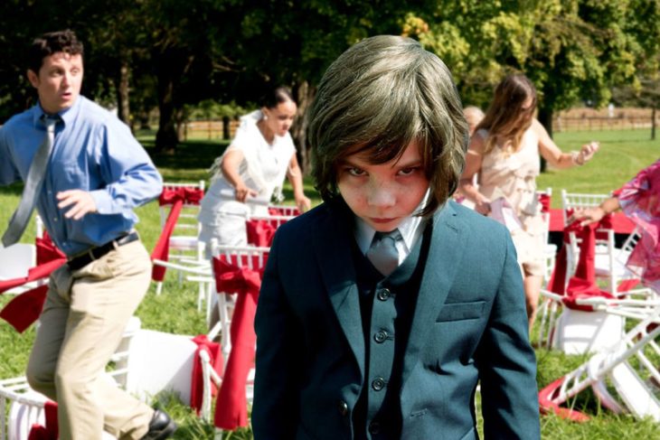 Película Pequeño demonio; niño con traje y mirada enojada, en una fiesta