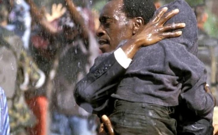 Don Cheadle cargando a un niño y corriendo bajo la lluvia, escena de la película Hotel Rwanda 