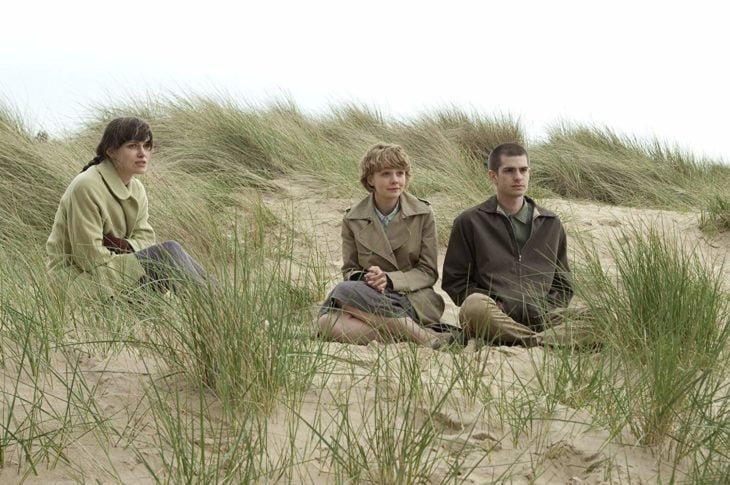 Keira Knightley, Carey Mulligan y Andrew Garfield sentados sobre la tierra seca, escena de la película Nunca me abandones 