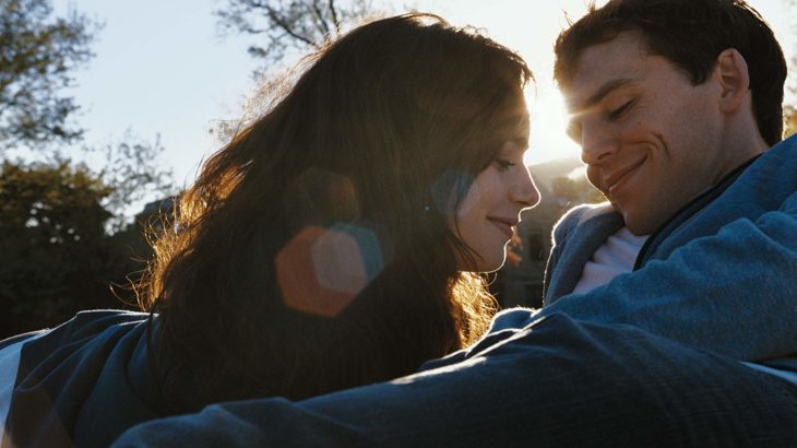 Lily Collins recostada sobre Sam Claffin en un parque sonriendo, escena de la película Love, Rosie 