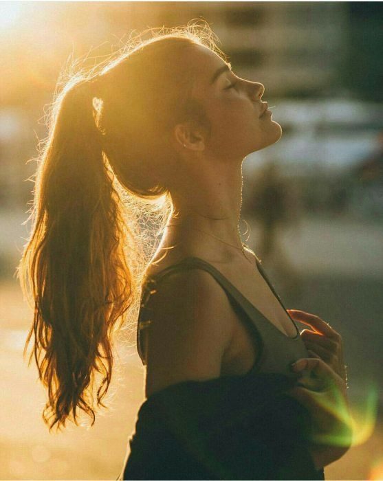 A contra luz, siluta de una chica joven delgada con cabello agarredo