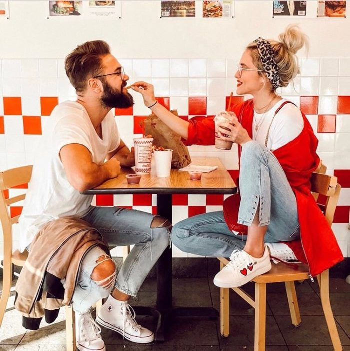 Pareja de novios comiendo papas fritas dentro de un restaurante