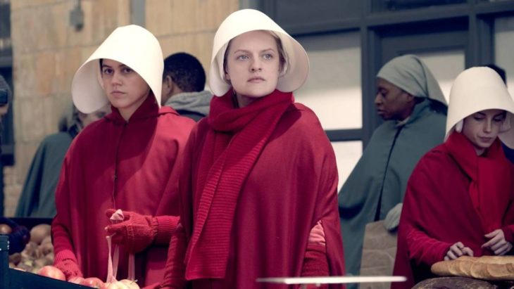 Escena de la serie El cuento de la criada. Mujeres vestidas de rojo y usando un sombrero blanco 