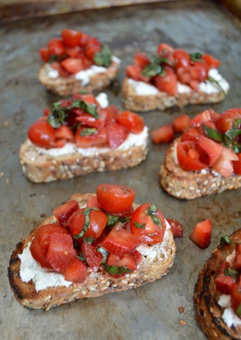 Tostadas gourmet con queso de cabra, rodajas de tomate, y fresas