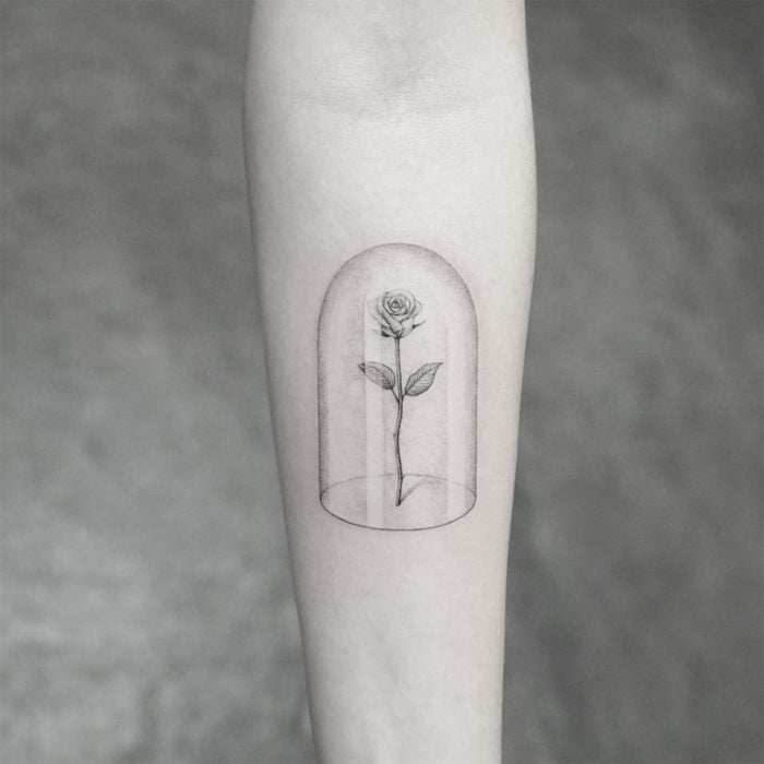 Tatuaje minimalista de la rosa de La Bella y la Bestia de Disney en el brazo