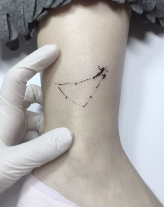 Tatuaje minimalista de Peter Pan volando en una constelación en el tobillo