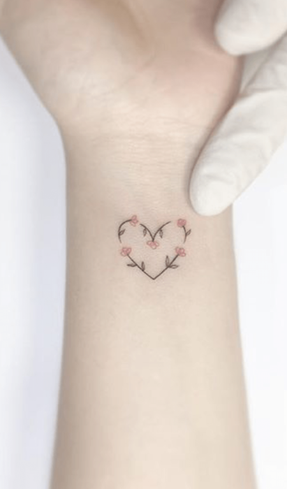 Diseño de tatuaje de flores que forman un corazón en la muñeca 