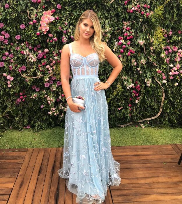 Ideas de vestidos para boda en jardín al aire libre; muchacha de cabello rubio y suelto con vestido estilo corsé color azul pastel, con tela de tul con flores tejidas