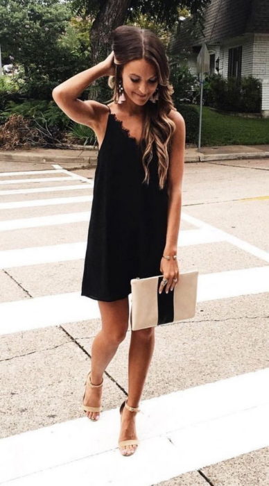 Chica usando un vestido negro estilo bata con sandalias nude y cartera nude 