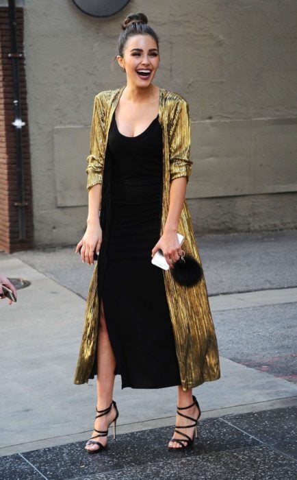 Chica usando un vestido de color negro con un ensamble dorado y bolsa clutch de terciopelo 