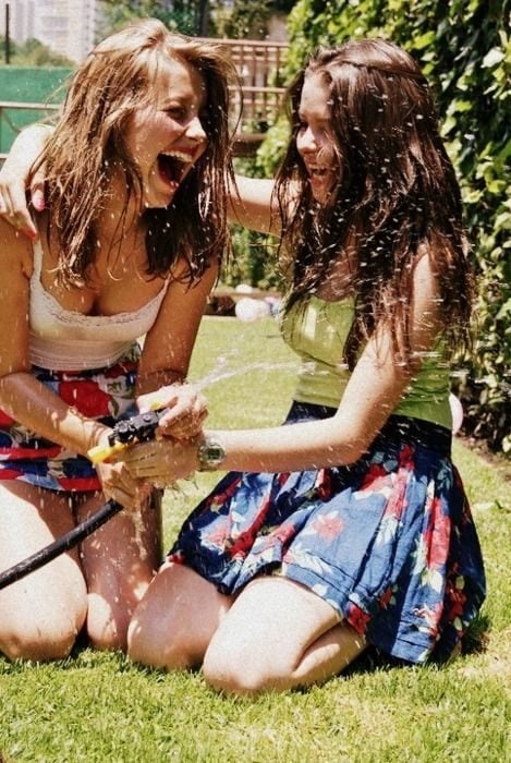 dos mujeres jóvenes riendo mientras se mojan con agua