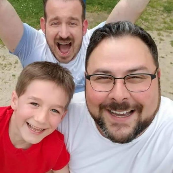 Paul y Gregg padres que adoptaron a un niño, posando para una selfie en la que sonríen 