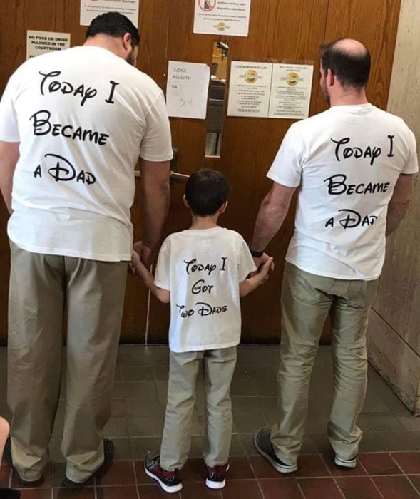 Paul y Gregg pareja que adoptó a un niño, celebrando la adopción con camisas del rey león que dicen "hoy me convertí en papá" 