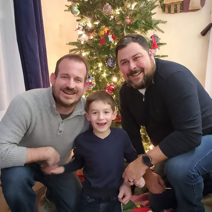 Paul y Gregg padres que adoptaron a un niño, posando para una selfie en la que sonríen mientras celebran la Navidad 