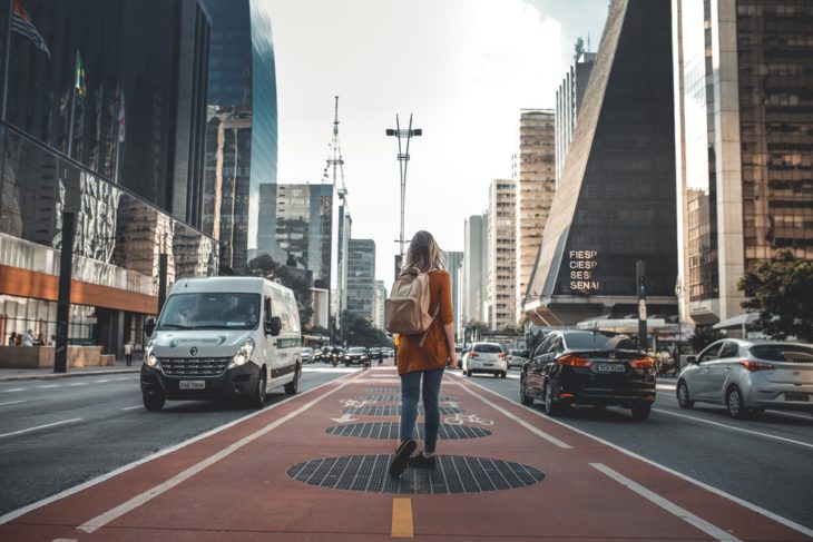 Chica a mitad de avenida admirando los edificios a su alrededor mientras modela para fotografía