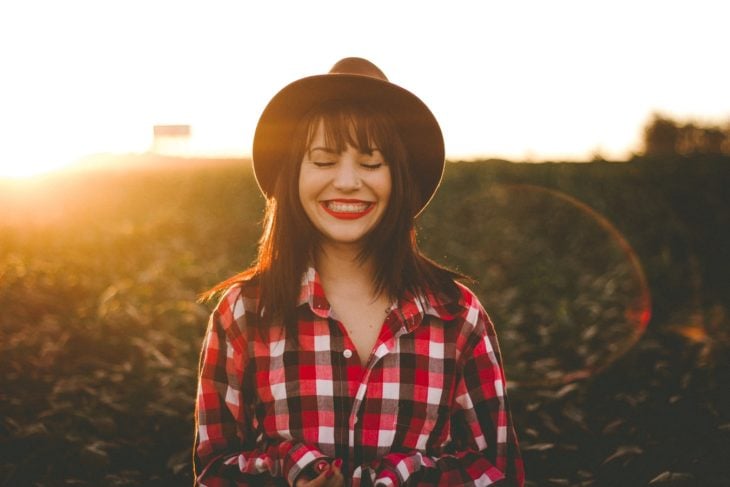 chica con sombrero sonriendo en el campo