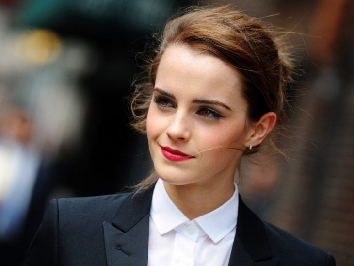Emma Watson sonriendo ligeramente y llevando traje sastre 
