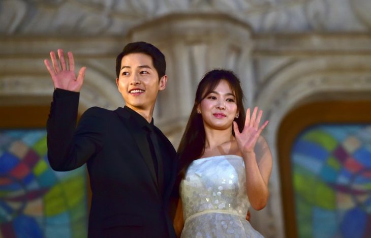 Actores song joong ki y song hye kyo saludando a sus fanaticos durante una alfombra roja 