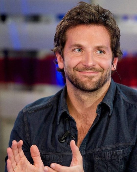 Actor, director y cantante Bradley Cooper sonriendo con una camisa de mezclilla 