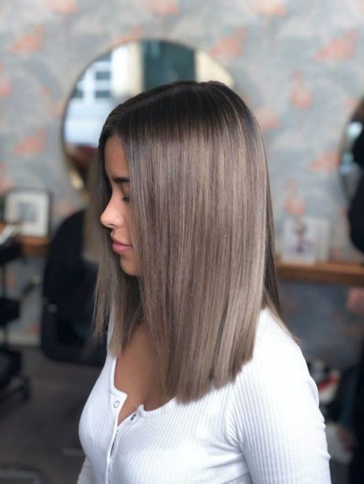 Chica dentro de un salón de belleza, de perfil, mostrando su cabello color rubio champiñón 