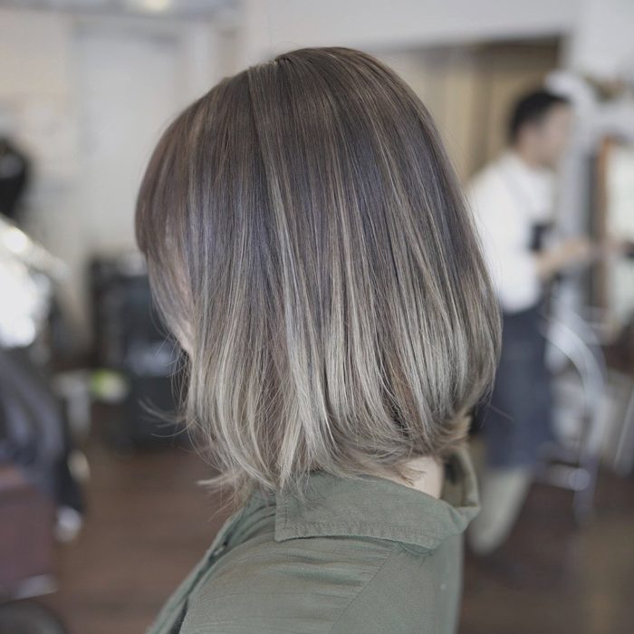 Chica sentada en un sal+on de belleza, de lado, mostrando su cabello color rubio champiñón 