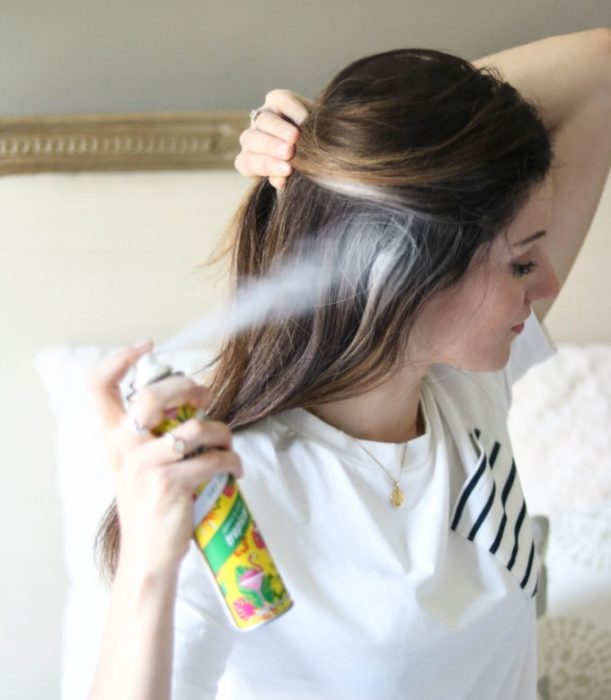 Champú en seco; mujer aplicando spray en el cabello