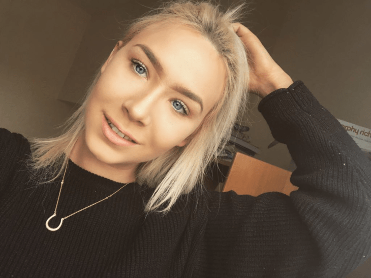 Chlo Matthews, chica rubia de ojos azules con suéter negro