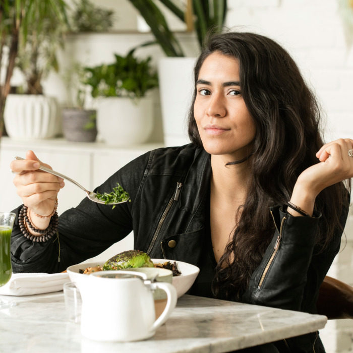 Daniela Soto-Innes comiendo vestida de negro levantando una cuchara con vajilla blanca