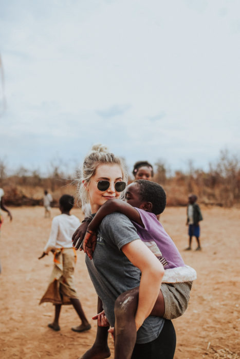 Cosas que debes hacer en vez de enamorarte; chica rubia cargando a un niño moreno en voluntariado