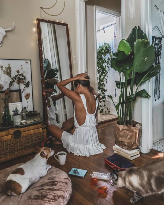 Cosas que debes hacer en vez de enamorarte; chica con vestido blanco sentada en el suelo mirándose al espejo con un perro y un gato