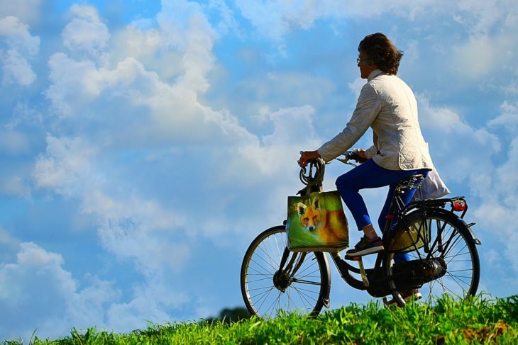 Mujer madura en bicicleta paseando por un prado