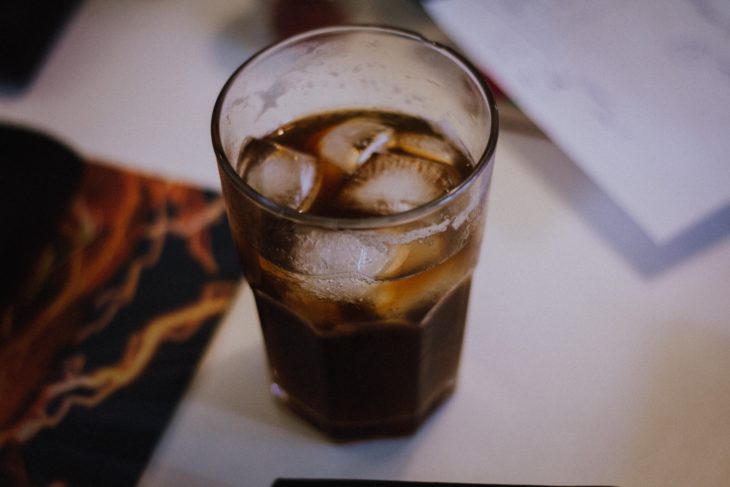 vaso de soda con hielos sobre una mesa blanca