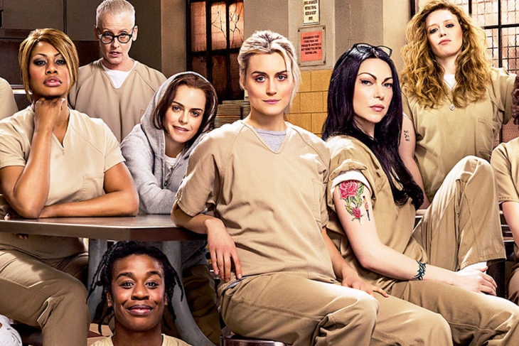 Escena de la serie de netflix orange is the new balck. Reclusas con el uniforme sentadas en el comedor 