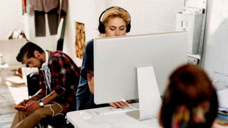 mujer trabaja frente a una computadora con audífonos puestos