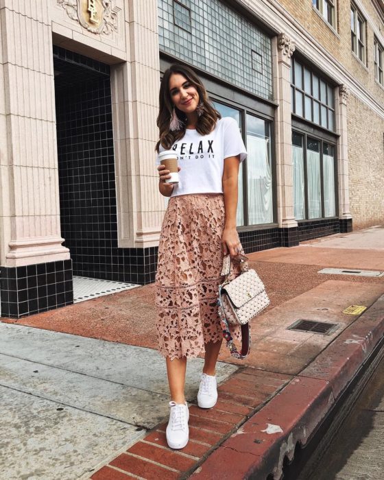 Faldas para el verano; chica caminando en la calle con café en la mano y falda color salmón de encaje