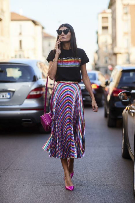 Faldas para el verano; mujer de cabello lacio, con lentes en forma de corazón, camisa casual y falda de satín de colores del arcoíris 