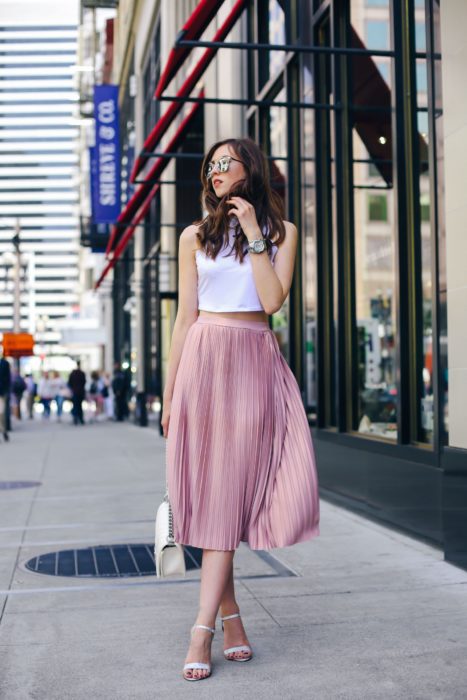 Faldas para el verano; chica caminando en la calle, con lentes de sol, top blanco y falda de satín larga color rosa