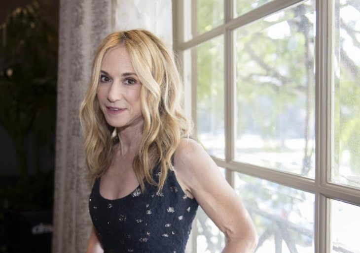 Holly Hunter recargada en una ventana con marco de madera