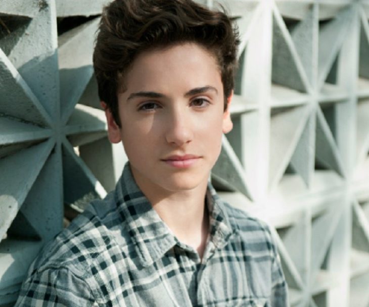 Teo Halm recargado en una pared de metal, posando pata una fotografía