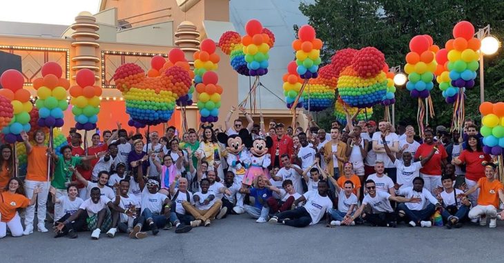 Magical Pride en Disneylandia; gente con Mickey y Minnie Mouse, con globos en forma del ratón de colores del arcoiris 