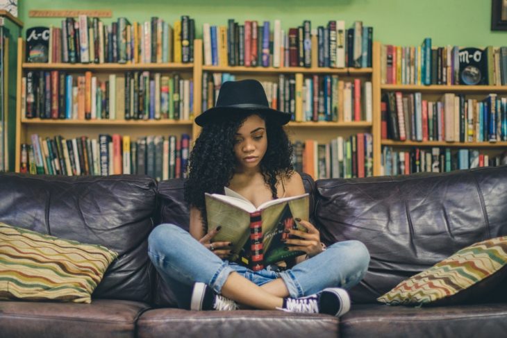 Chica sentada en un sofá leyendo un libro