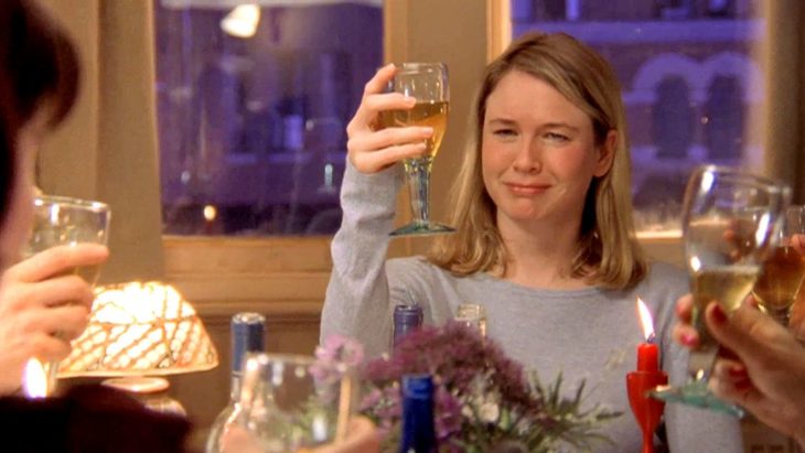 Escena de el diario de bridget Jones. Bridget brindando con una copa en una reunión familiar 