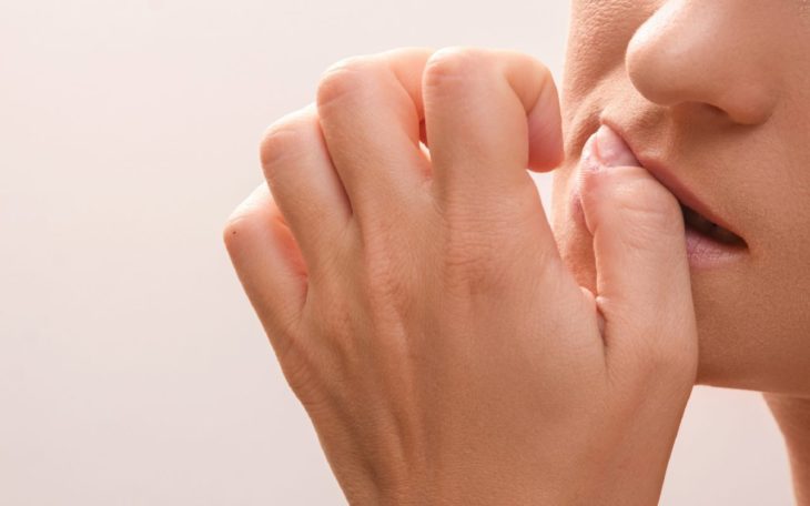 una mujer se muerde la uña del dedo gordo de la mano izquierda no se le ve la cara completa