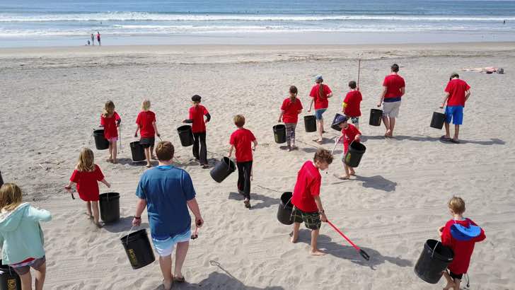 Niños limpiando una playa de manera exhaustiva para que no contamine el mar 