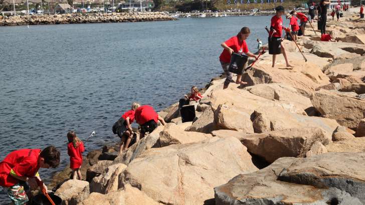 Niños sobre las rocas limpiando las playas de la basura y la contaminación 